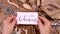 Hands with BOHEMIAN handwritten card over a wooden table top view