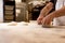 Hands of bread baker kneading fresh and uncooked bread dough on table during bread preparation process in bakery house. concept of