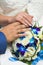 Hands of bride and groom with golden wedding rings and blue and white wedding bouquet