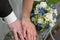 Hands of bride and groom with wedding bouquet
