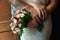 Hands of the bride and groom with wedding rings, bride holds a wedding bouquet in hands, the groom hugs her from behind