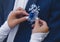 Hands of the bride in wedding gloves touch the decoration in the form of a rose flower on a blue suit of the groom, close-up