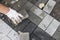 Hands of a builder in his orange gloved hands with a hammer fitting laying new exterior paving stones carefully placing