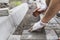 Hands of a builder in his orange gloved hands with a hammer fitting laying new exterior paving stones carefully placing