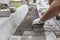 Hands of a builder in his orange gloved hands with a hammer fitting laying new exterior paving stones carefully placing