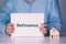 Hands of businessman holding refinance word on notebook and home model, finance and residential.