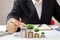 The hands of businessmen are planting trees growing on coins, including notebooks on wooden desks for work.