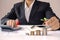 The hands of businessmen are planting trees growing on coins, including notebooks on wooden desks for work.