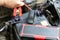Hands of car mechanic using portable car jump starter to start-up engine. Close up view