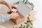 Hands carefully placing small jar with honey in a box with filling paper