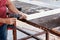 Hands of a carpenter drills or screws a wooden plank frame with an electric screwdriver