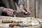 Hands of carpenter plane on workbench in carpentry