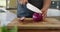 Hands of caucasian pregnant woman wearing apron and cutting onion