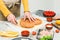 Hands of a caucasian teenage girl in an apron cut out the dough in the shape of a heart for pizza.