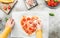 Hands of a caucasian teenage girl pouring grated cheese on pizza hearts .