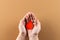 Hands of caucasian woman cupping blood drop on brown background