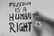 Hands of caucasian woman hitting table with fists next to protest poster with words `Freedom is a Human Right