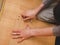 The hands of a Caucasian young man are tightening a bolt on the wooden part of the bed