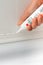 Hands caulking bath tube with white silicone glue