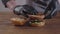 Hands of the chef in black kitchen gloves making burger close-up. The cook putting cutlet on tomato slices and basil