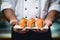 The hands of a chef holding a plate of freshly prepared sushi rolls - Japanese traditional food