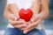 Hands of child and adult woman holding red heart,