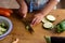 Hands of a child, with an apron, cutting zucchini, helping to prepare the dinner, at a table full of vegetables