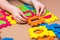 Hands of a child assemble a color puzzle with details of different geometric shapes on the table.