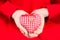 Hands of a child holding a plaid red-white textile heart with button