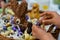 Hands of a child unwrap a chocolate candy egg with a large Easter egg basket in the background during Easter cellebrations