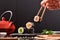 Hands with chopsticks picking sushi on table front view dark