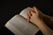Hands clasping and open Bible with black background, praying to God, coronavirus