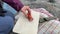 Hands close-up. Girl tourist at a halt cuts sausage with a knife on the board.