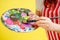 Hands closeup of artist painter in an apron palette, tube of paint , brushes on a pink background in studio . muse and