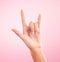 Hands, closeup and woman in studio with rock and roll sign, gesture or symbol against pink background. Zoom, rebel and