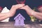 Hands closing toy house of lavender color,