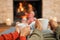 Hands, coffee and couple relax by fireplace, bonding and cozy in home together. Tea, man and woman relaxing by fire on