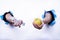 Hands coming out of a white background holding a tape measure and an apple