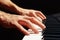 Hands of composer play the keys of the piano on black background close up