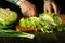 The hands of the cook cut fresh green cabbage on a cutting board with a knife. Close-up of a chef hands while working on a kitchen