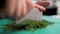 Hands of the cook. Cutting greens. The dill is finely chopped on a cutting board. Dark background