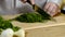 Hands of the cook knife big kitchen a fresh green fennel on a chopping board from a tree