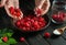 Hands of a cook sorts through fresh raspberries before preparing a sweet fruit drink. Preparing jam or compote on the kitchen