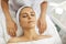 Hands of cosmetologist relaxing on towel near womans face after facial massage