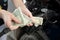 Hands counts crumpled dollar bills against the background of fueling car