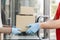 Hands of courier in protective gloves gives boxes to customer at doors