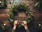 Hands crafting a festive Christmas wreath on wooden table