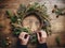 Hands crafting a natural Christmas wreath on a wooden table