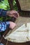 The hands of a craftsman stringing a chair bottom.