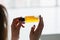 Hands of cropped white woman holding cosmetic serum bottle with pipette near window. Texture of serum